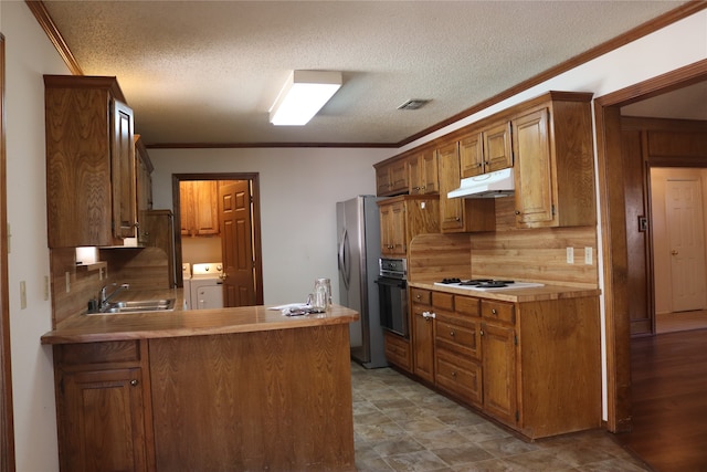 kitchen with kitchen peninsula, a textured ceiling, washing machine and clothes dryer, stainless steel refrigerator, and white gas cooktop