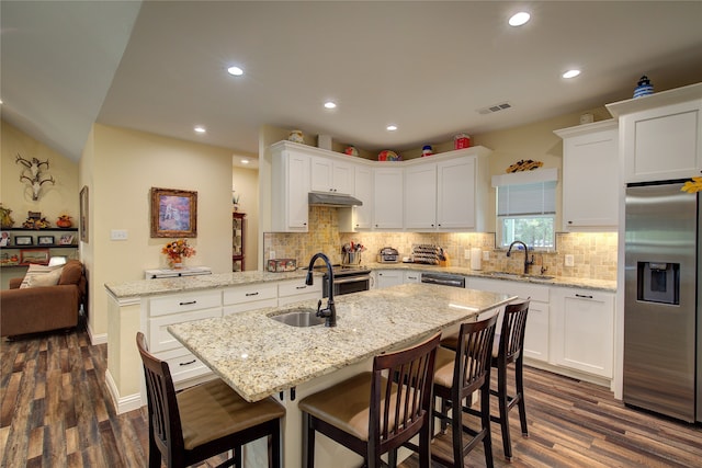 kitchen with light stone countertops, sink, dark hardwood / wood-style flooring, a kitchen breakfast bar, and stainless steel appliances