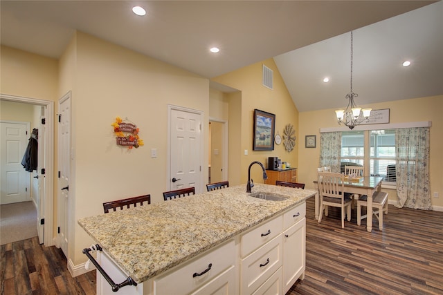 kitchen with dark hardwood / wood-style floors, an island with sink, sink, pendant lighting, and white cabinetry