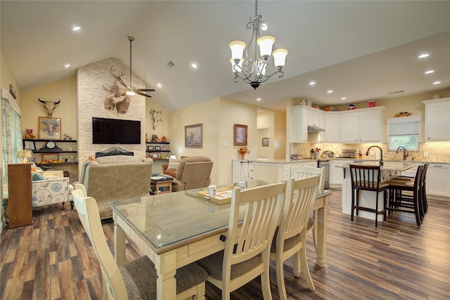 dining room with high vaulted ceiling, dark hardwood / wood-style flooring, ceiling fan with notable chandelier, and a stone fireplace