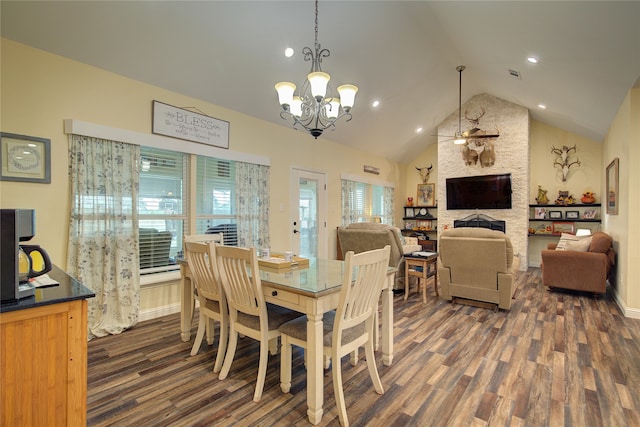 dining area with vaulted ceiling, a stone fireplace, ceiling fan with notable chandelier, and dark hardwood / wood-style flooring