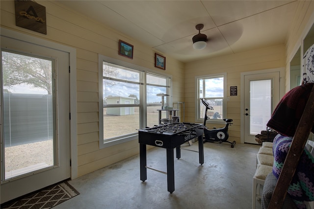 rec room featuring wood walls and ceiling fan