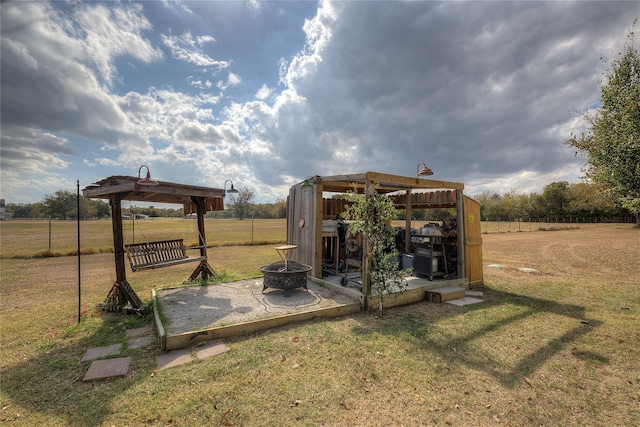 view of yard featuring an outdoor structure, a fire pit, and a rural view