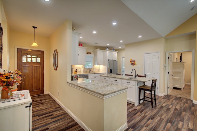 kitchen featuring a kitchen island, hanging light fixtures, sink, stainless steel fridge, and white cabinets