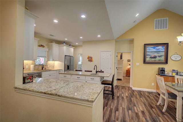 kitchen with light stone countertops, appliances with stainless steel finishes, dark hardwood / wood-style flooring, a center island, and white cabinets