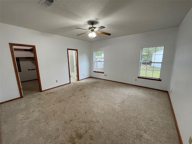 unfurnished bedroom featuring carpet, a walk in closet, and ceiling fan