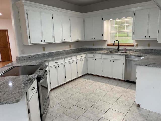 kitchen featuring appliances with stainless steel finishes, white cabinetry, dark stone countertops, and sink