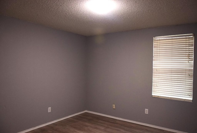 empty room with a textured ceiling and dark hardwood / wood-style floors