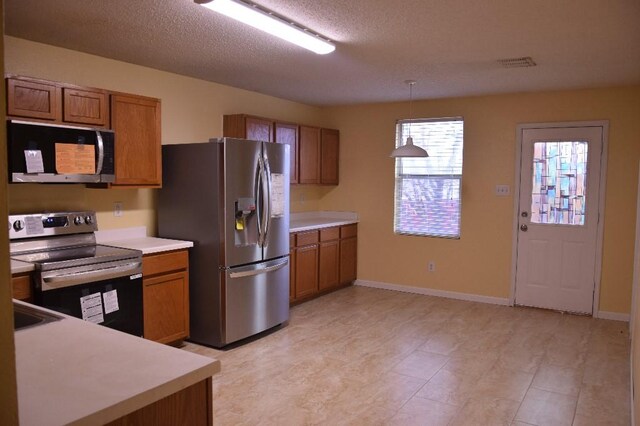 kitchen featuring a textured ceiling, stainless steel appliances, and decorative light fixtures