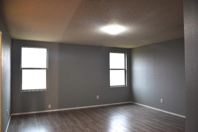 unfurnished room featuring dark wood-type flooring and a textured ceiling