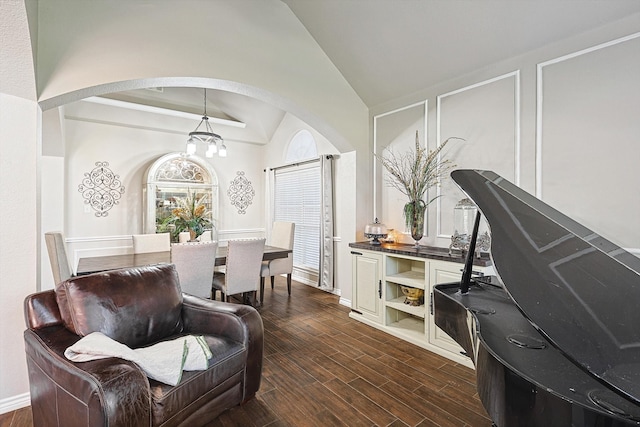 interior space featuring arched walkways, dark wood-type flooring, an inviting chandelier, and vaulted ceiling