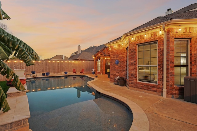 pool at dusk with a patio area