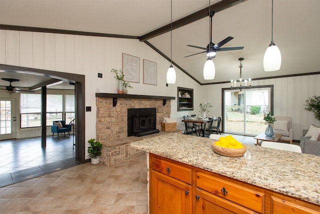 kitchen featuring light stone countertops, plenty of natural light, lofted ceiling with beams, and decorative light fixtures