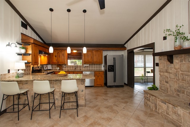 kitchen featuring hanging light fixtures, decorative backsplash, light stone counters, kitchen peninsula, and stainless steel appliances