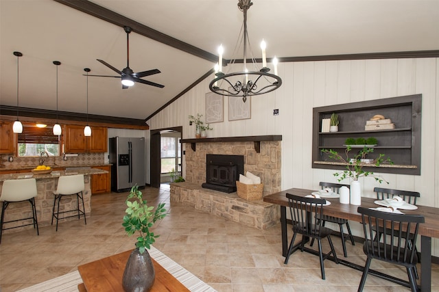 living room with a wood stove, crown molding, plenty of natural light, and ceiling fan with notable chandelier