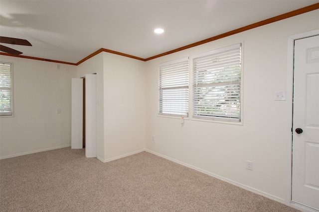 spare room featuring ceiling fan, light colored carpet, and crown molding