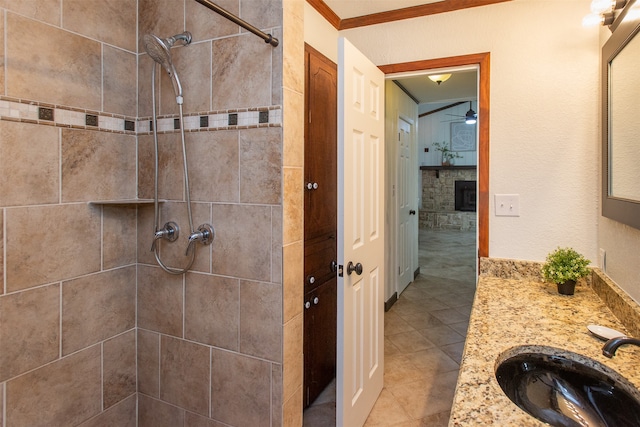 bathroom featuring a tile shower, vanity, ceiling fan, crown molding, and tile patterned flooring