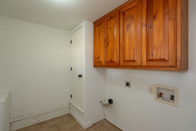 clothes washing area with cabinets, washer hookup, electric dryer hookup, a textured ceiling, and light tile patterned flooring