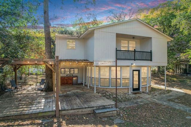 back house at dusk featuring area for grilling and a wooden deck