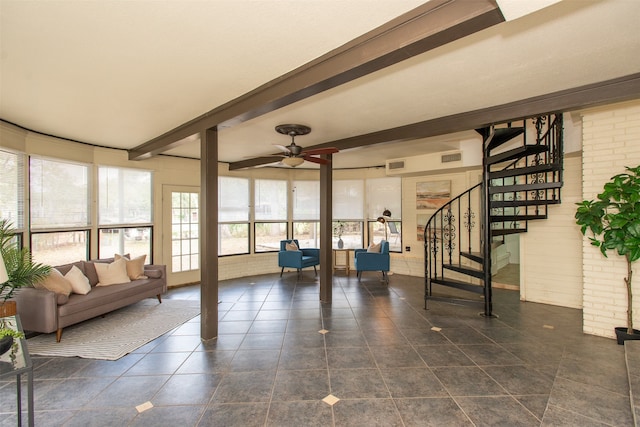 interior space with dark tile patterned flooring, plenty of natural light, beam ceiling, and ceiling fan