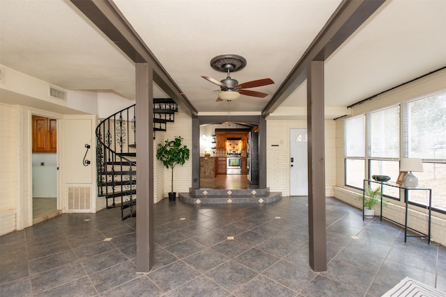 entrance foyer featuring ceiling fan, crown molding, and brick wall