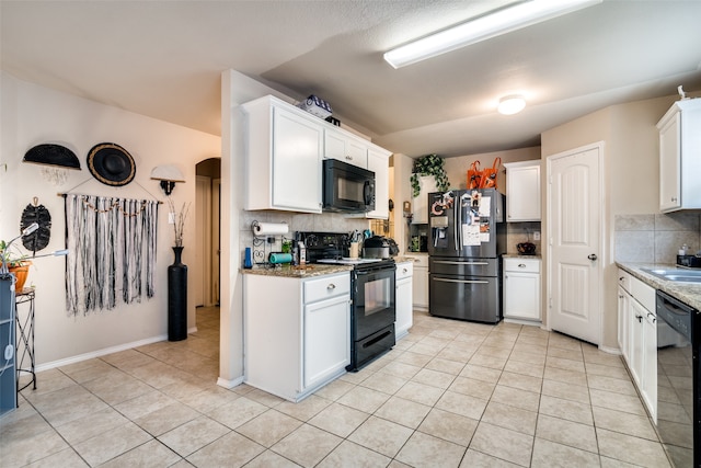 kitchen with white cabinetry, black appliances, light stone counters, and backsplash