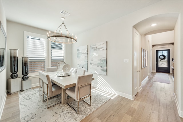 dining space with light hardwood / wood-style flooring and a chandelier