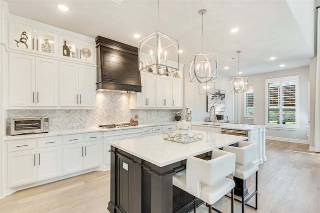 kitchen featuring premium range hood, white cabinets, a center island, and hanging light fixtures