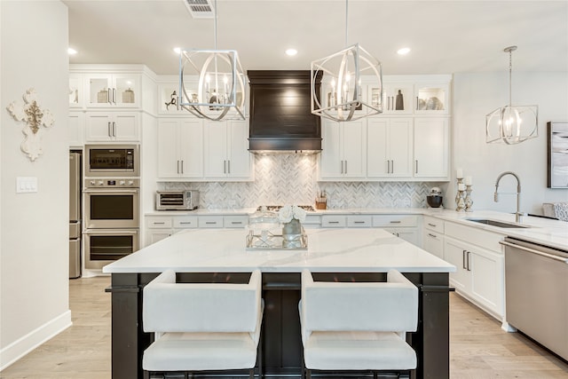 kitchen with custom exhaust hood, light stone counters, a breakfast bar area, and stainless steel appliances