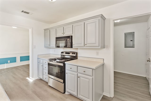 kitchen with stainless steel range, electric panel, light wood-type flooring, and gray cabinetry