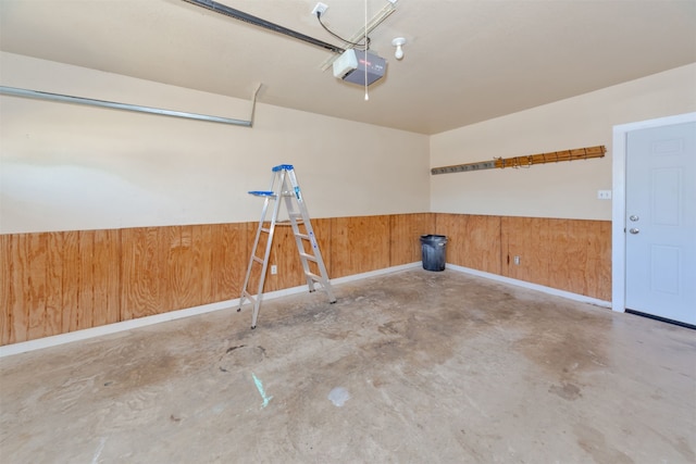 garage featuring a garage door opener and wooden walls