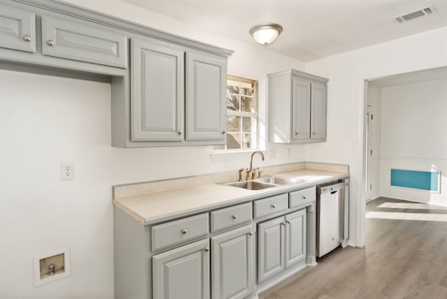 kitchen featuring white dishwasher, sink, gray cabinetry, and light hardwood / wood-style floors