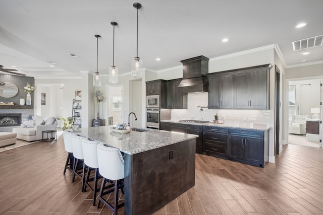 kitchen with sink, light stone countertops, a kitchen island with sink, and dark wood-type flooring