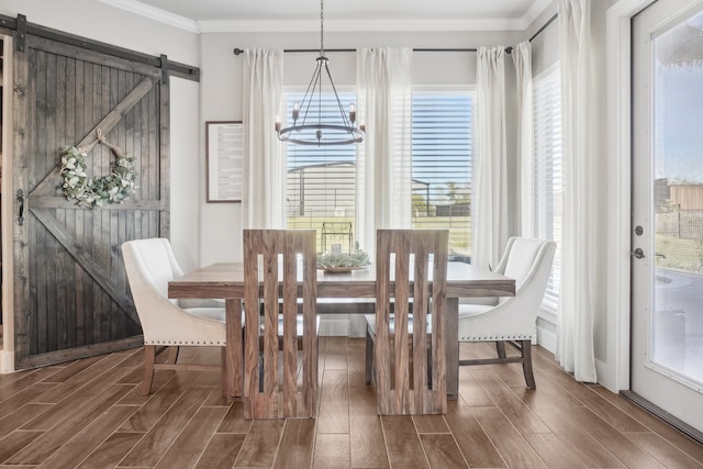 dining space featuring a barn door, crown molding, dark hardwood / wood-style flooring, and plenty of natural light