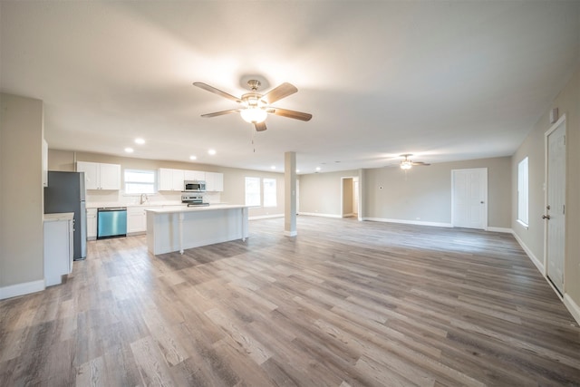 unfurnished living room featuring ceiling fan, light hardwood / wood-style floors, and sink