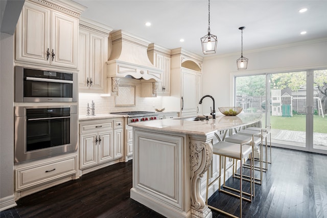 kitchen featuring cream cabinets, dark hardwood / wood-style flooring, an island with sink, stainless steel appliances, and sink