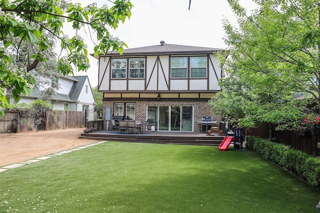 back of house featuring a wooden deck and a lawn