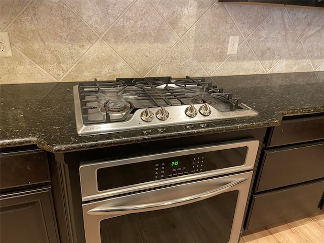 details featuring decorative backsplash, stainless steel appliances, and dark stone counters