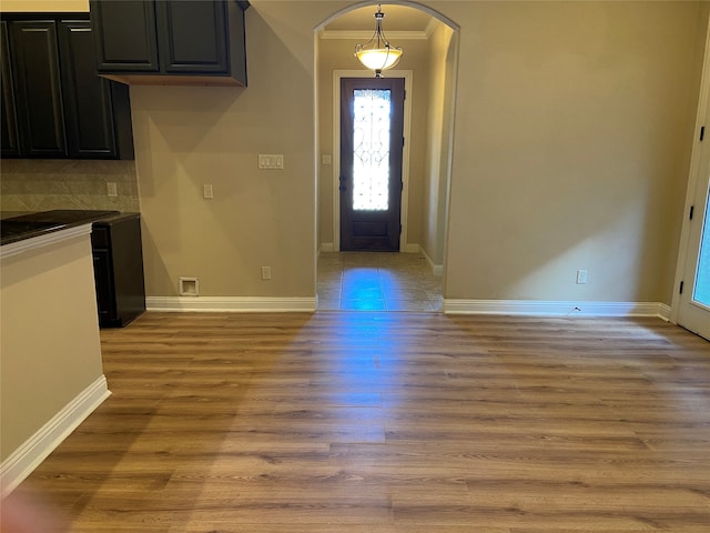 interior space featuring pendant lighting, hardwood / wood-style floors, decorative backsplash, and crown molding