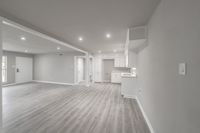 unfurnished living room with light hardwood / wood-style floors and sink