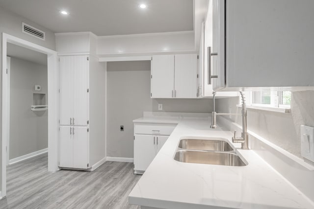 kitchen with light hardwood / wood-style floors, sink, and white cabinetry