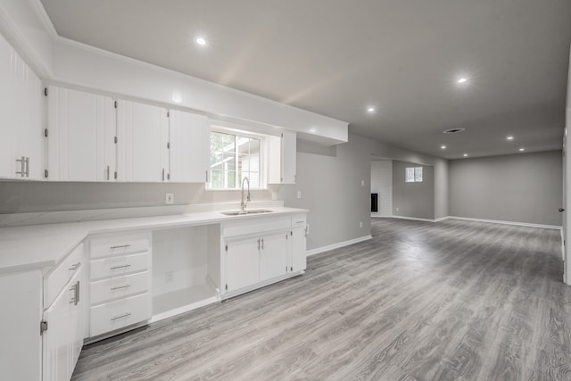 kitchen featuring white cabinetry, a fireplace, light hardwood / wood-style flooring, and sink