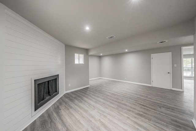 unfurnished living room with light wood-type flooring, a large fireplace, and plenty of natural light