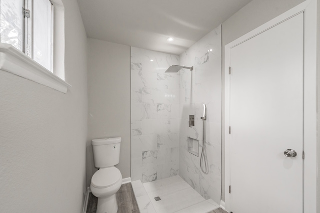 bathroom with toilet, hardwood / wood-style floors, and tiled shower