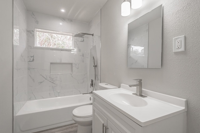 full bathroom featuring toilet, tiled shower / bath, and vanity