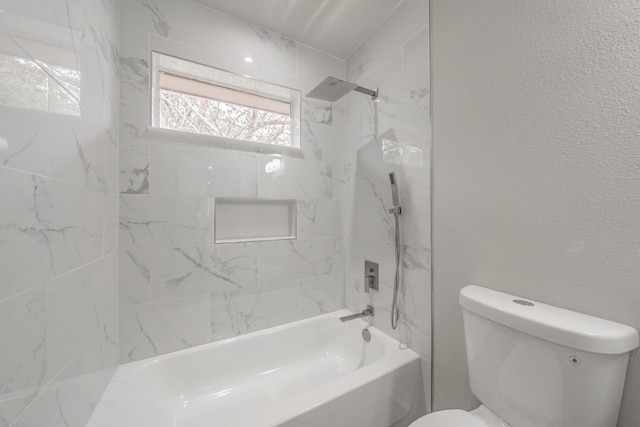 bathroom featuring tiled shower / bath combo and toilet