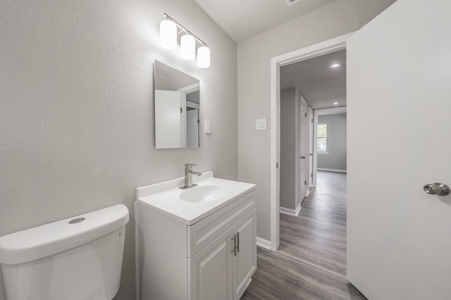 bathroom with toilet, hardwood / wood-style flooring, and vanity