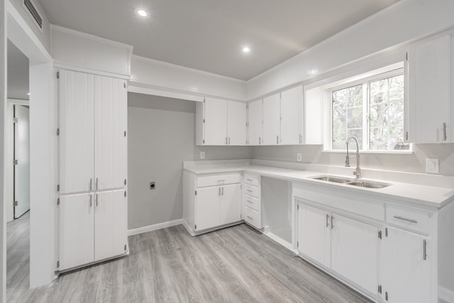 kitchen featuring crown molding, light hardwood / wood-style floors, white cabinets, and sink