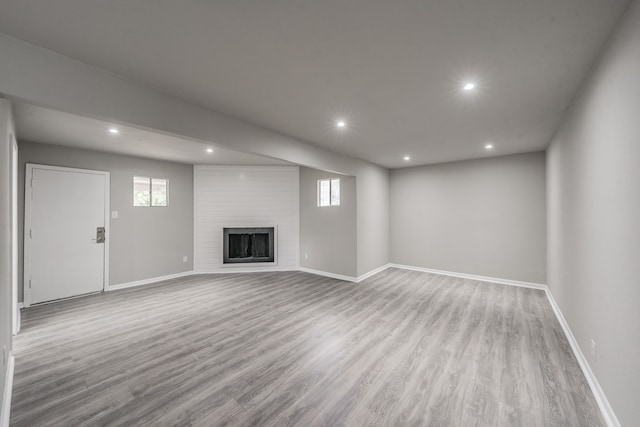 unfurnished living room with a large fireplace and light wood-type flooring