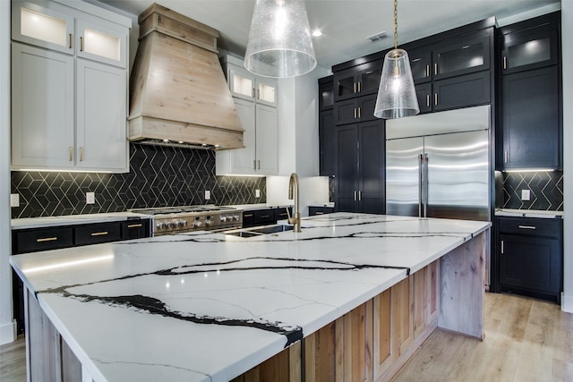 kitchen with hanging light fixtures, stainless steel appliances, a large island, white cabinetry, and premium range hood